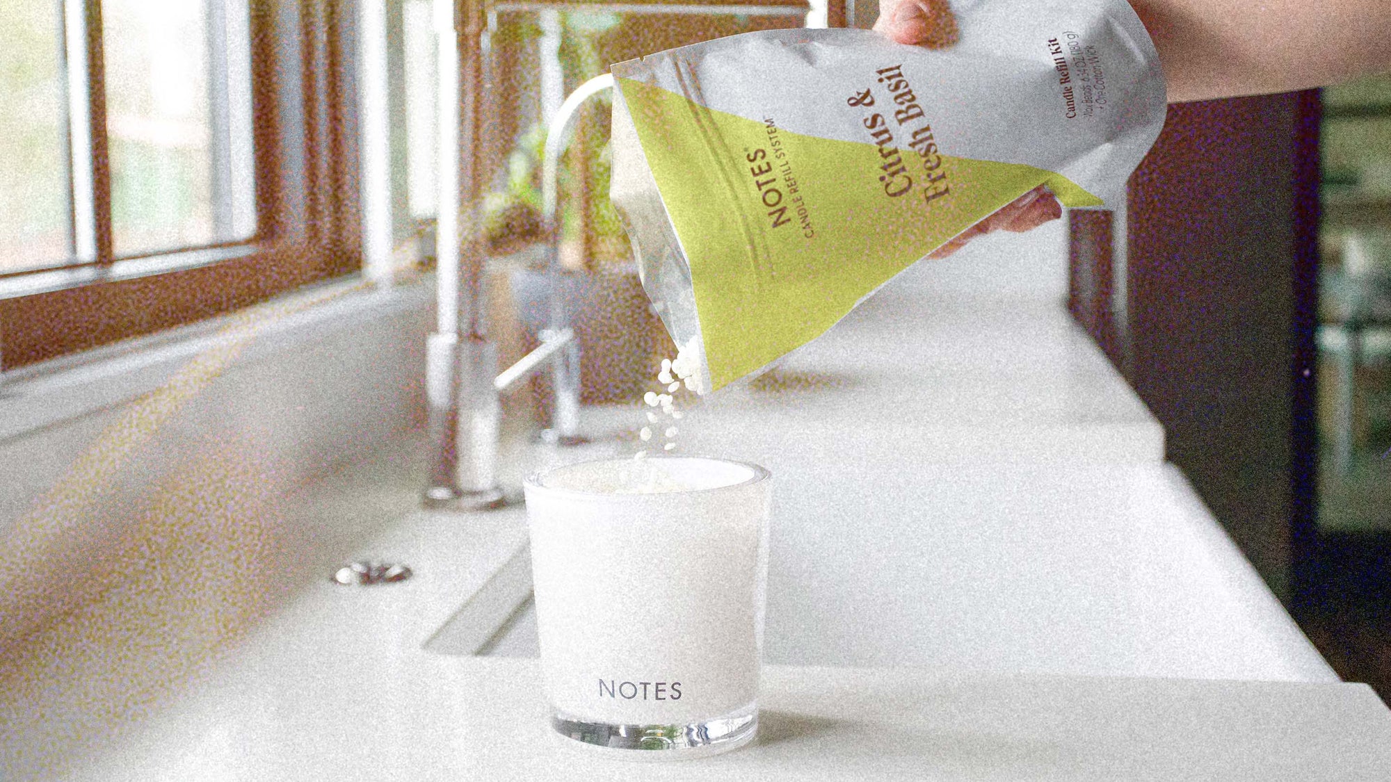 Refilling candle with scented wax beads on kitchen counter