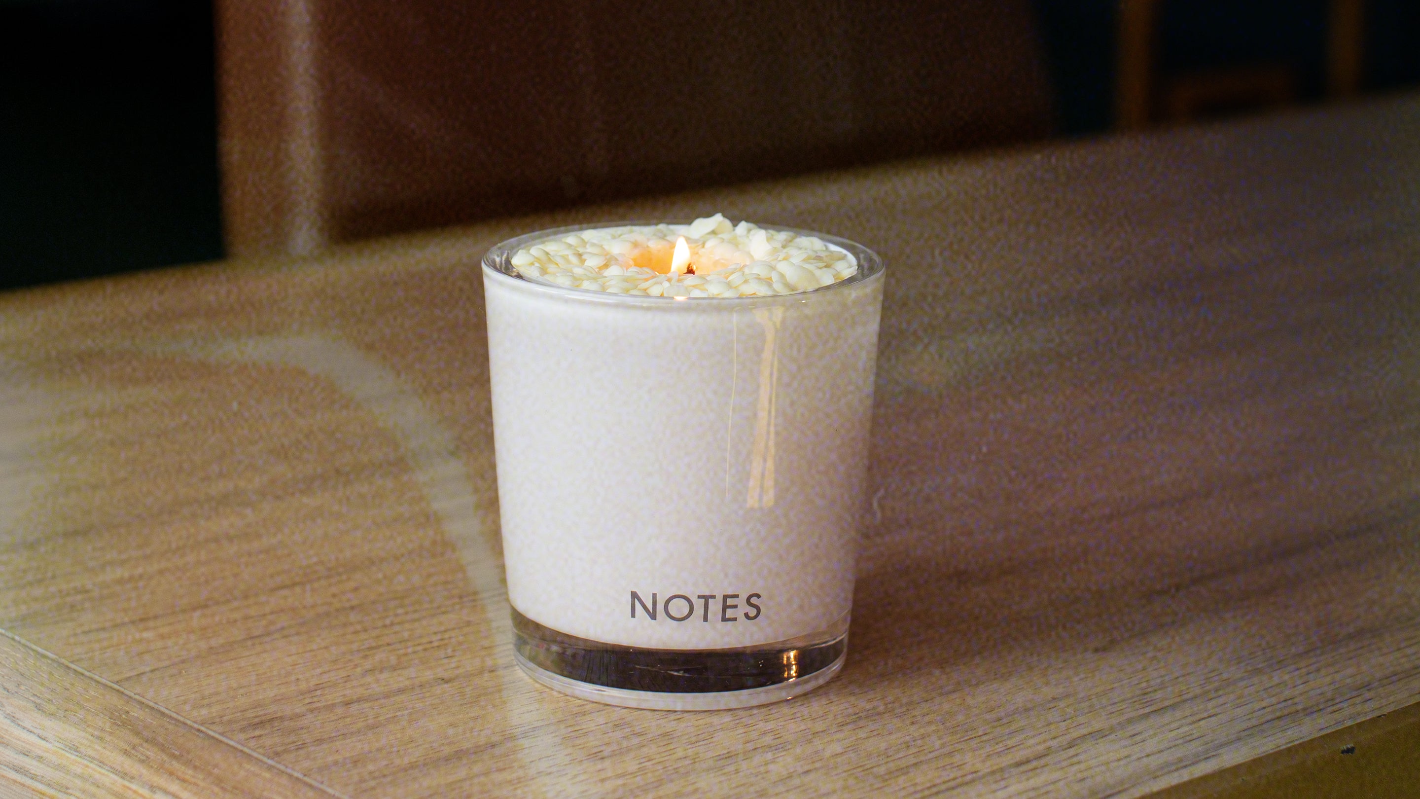 White candle vessel - NOTES - sitting on wood grain table