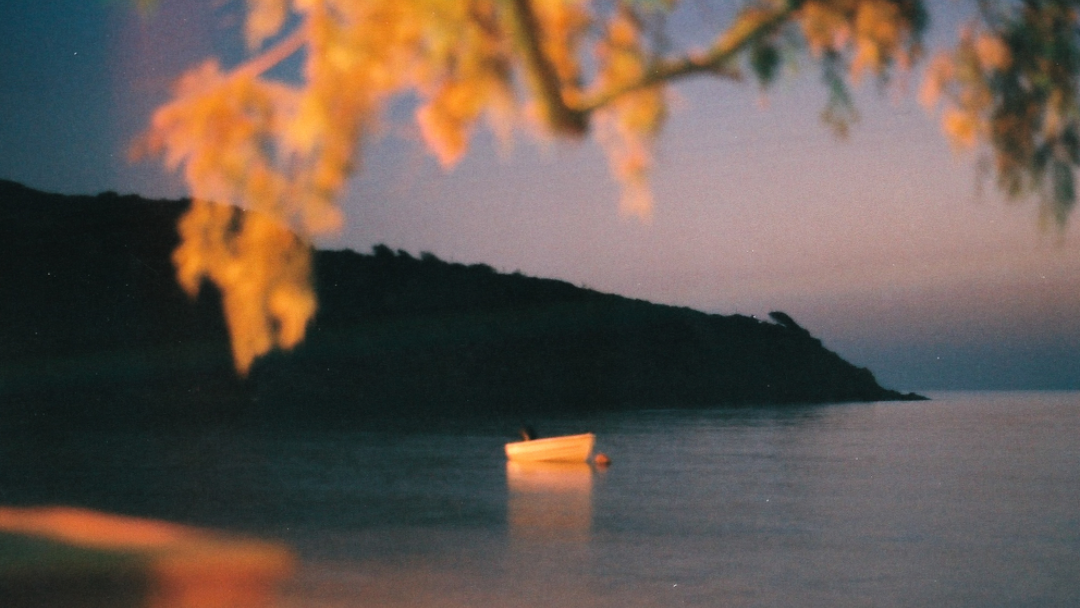 Film photo: Boat in lake with mountain backdrop.