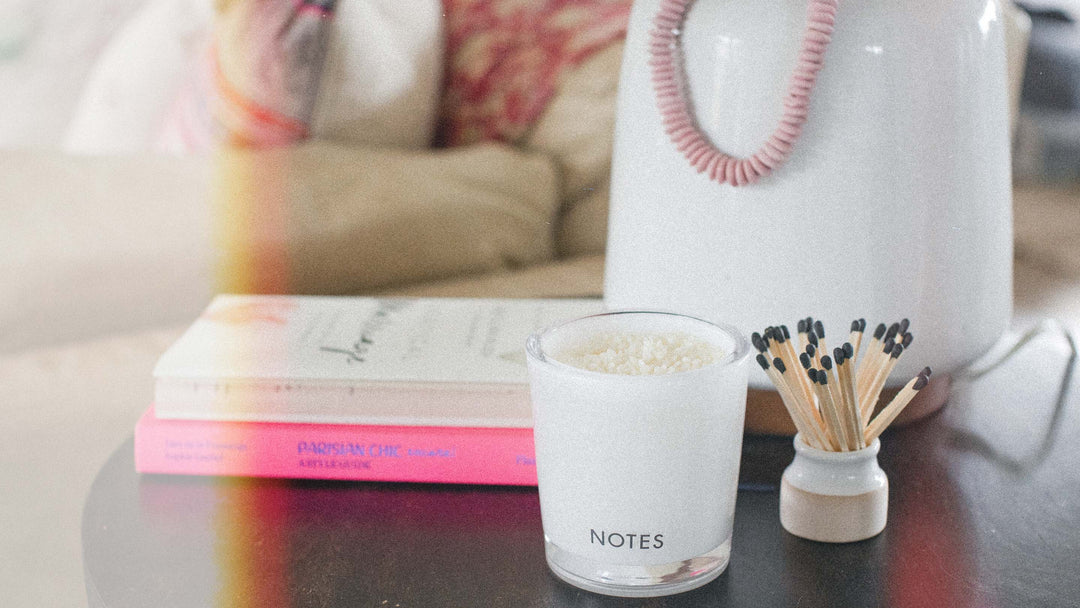 NOTES® Candle Refill sitting on top of coffee table with light flare