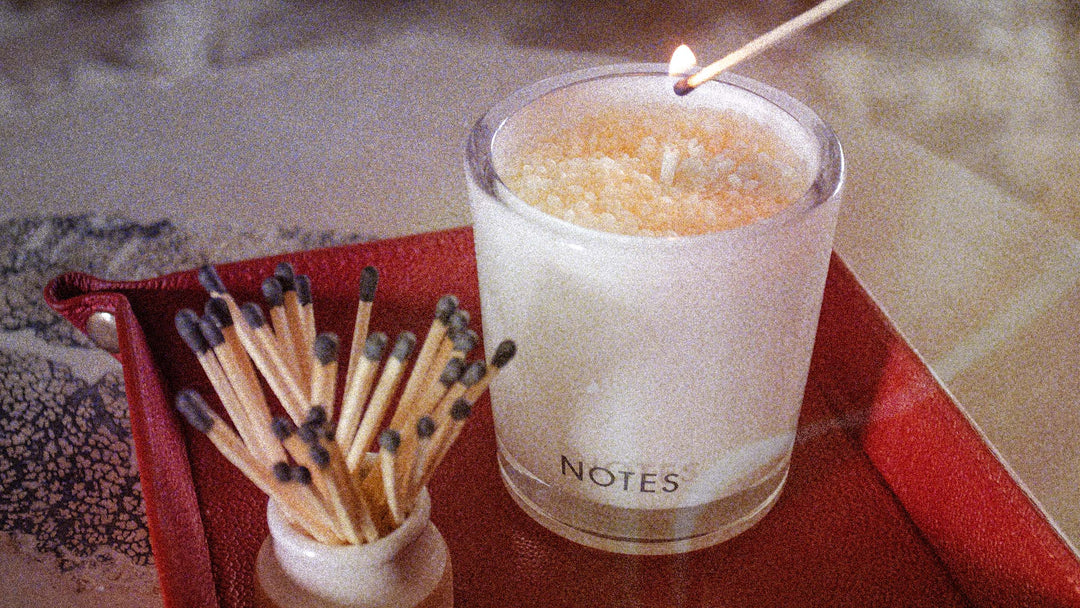 Granular photo of a NOTES Candle Refill being lit by a match. 